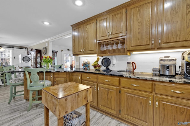 kitchen with tasteful backsplash, brown cabinetry, and dark stone countertops