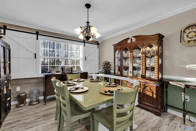 dining area featuring a chandelier, a barn door, light wood-style floors, and crown molding