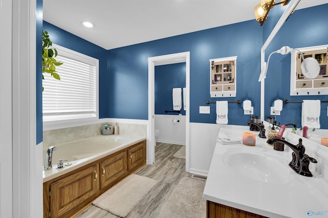 full bath featuring a bath, wood finished floors, vanity, and toilet