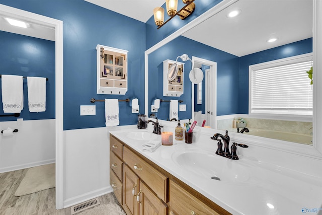 full bathroom featuring double vanity, visible vents, a sink, and wood finished floors