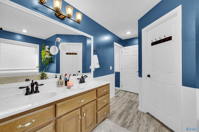 full bathroom with double vanity, a sink, and wood finished floors