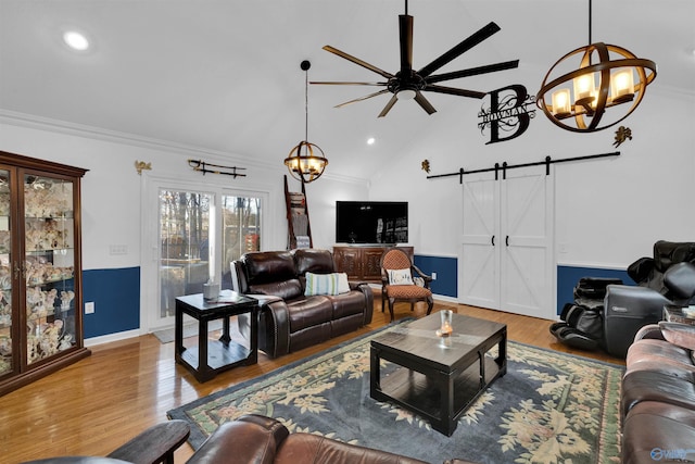 living area with lofted ceiling, a barn door, recessed lighting, ceiling fan with notable chandelier, and light wood finished floors