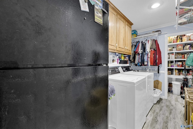 laundry room with cabinet space, light wood-style flooring, washer and clothes dryer, and crown molding