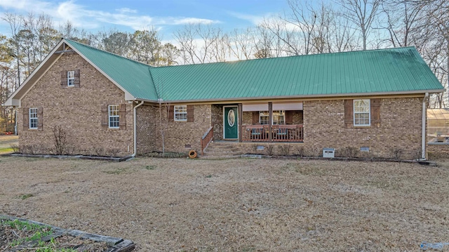 view of front of house featuring metal roof, brick siding, and crawl space