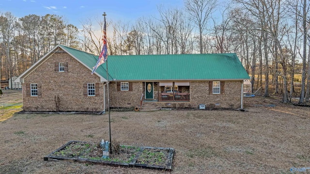 rear view of property featuring metal roof, brick siding, and crawl space