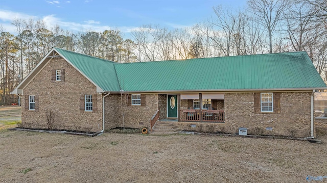 back of house with a porch, crawl space, brick siding, and metal roof