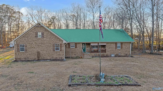 rear view of house with crawl space, a garden, metal roof, and brick siding