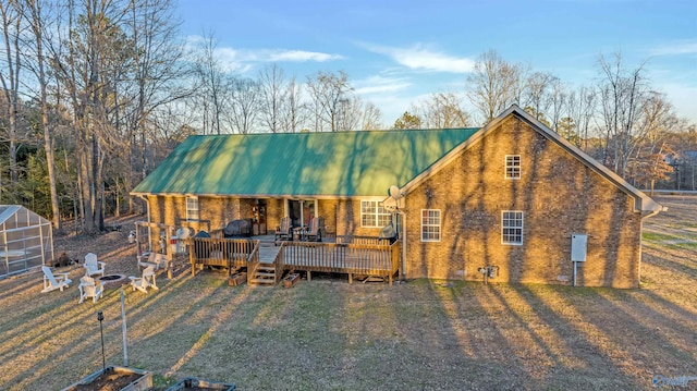 rear view of property with a fire pit, metal roof, an outbuilding, a wooden deck, and brick siding