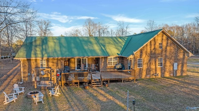 exterior space with a fire pit, metal roof, brick siding, and a deck