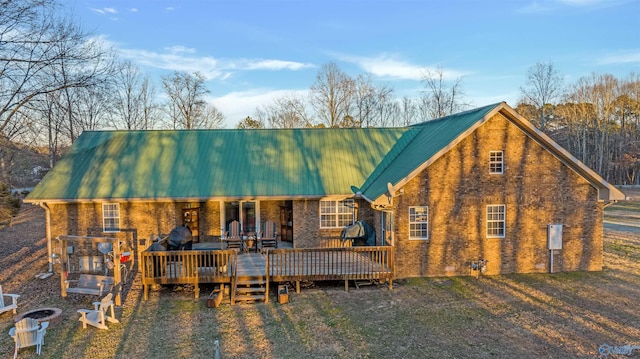 rear view of house with brick siding, metal roof, and a wooden deck