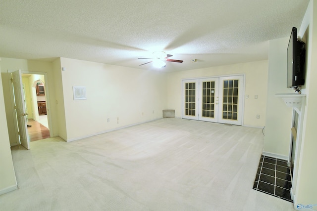 unfurnished living room featuring light carpet, french doors, a textured ceiling, and ceiling fan