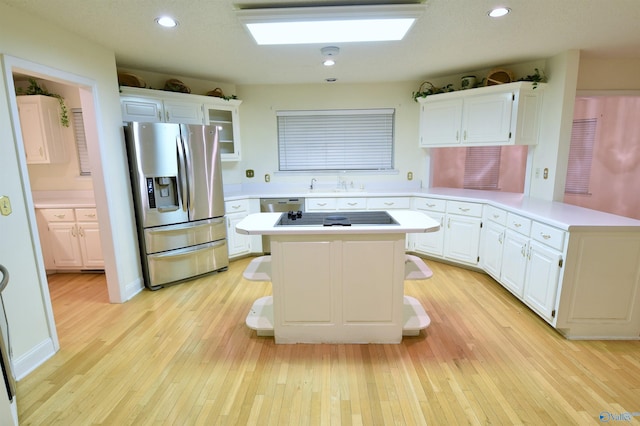 kitchen featuring kitchen peninsula, appliances with stainless steel finishes, light hardwood / wood-style flooring, white cabinets, and a kitchen island