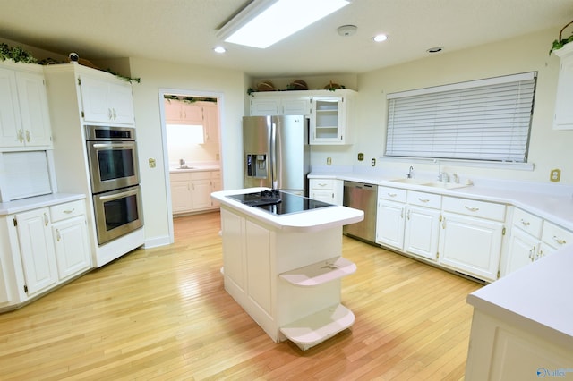 kitchen featuring sink, a center island, light hardwood / wood-style floors, white cabinets, and appliances with stainless steel finishes