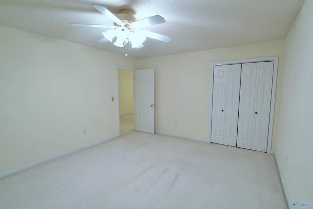 unfurnished bedroom featuring ceiling fan, a closet, light colored carpet, and a textured ceiling