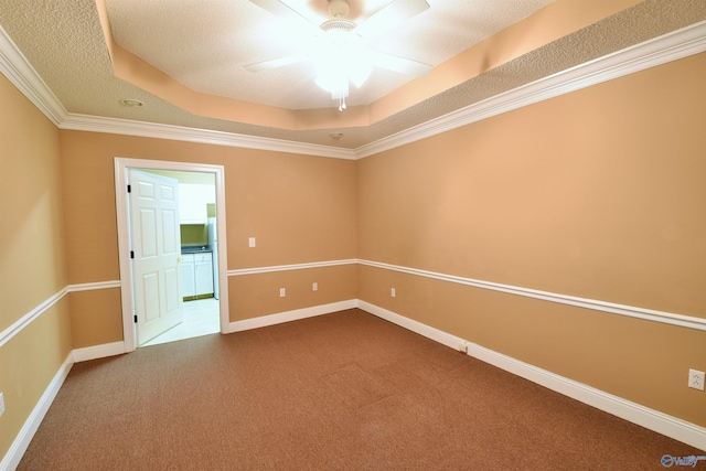 carpeted empty room with a raised ceiling, ceiling fan, and crown molding