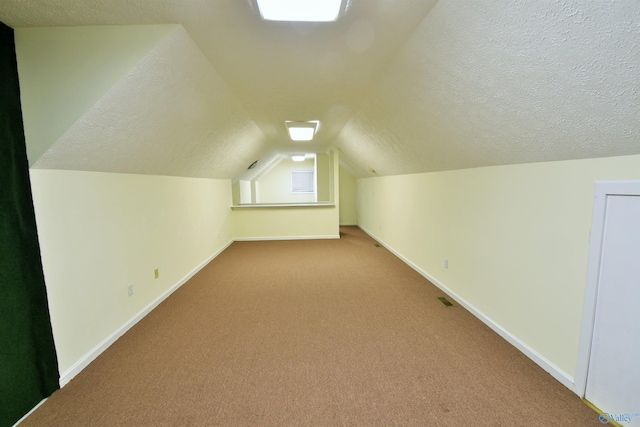 additional living space featuring a textured ceiling, light colored carpet, and lofted ceiling