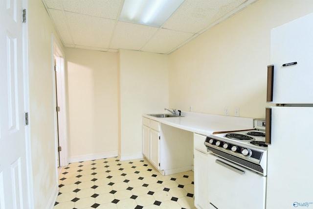 kitchen with white cabinets, a drop ceiling, white appliances, and sink