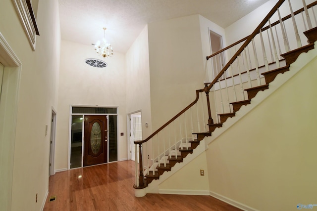 foyer entrance featuring hardwood / wood-style floors, a high ceiling, and an inviting chandelier