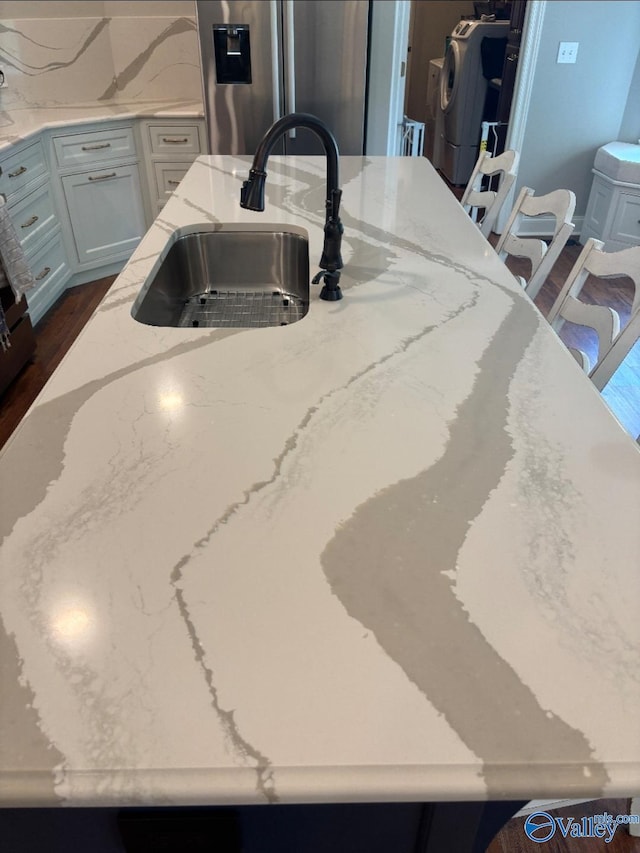103 Covey Ln, Hazel Green, AL 35750 - kitchen view of stainless steel refrigerator with ice dispenser, light stone countertops, decorative backsplash, washer / clothes dryer, and a kitchen island with sink