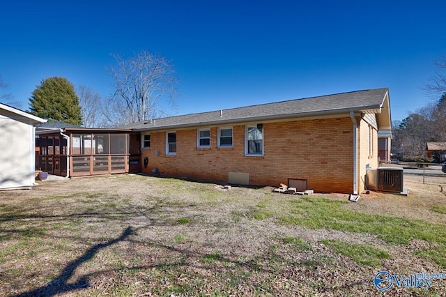 rear view of house with a lawn, central AC unit, and a sunroom