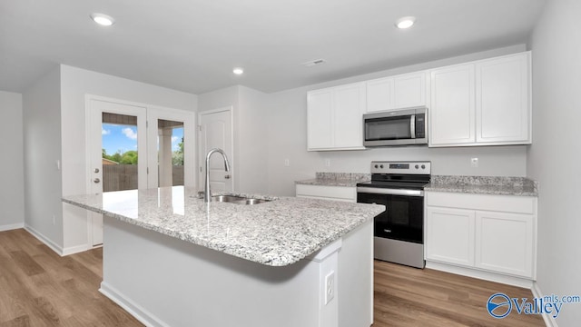 kitchen with white cabinets, stainless steel appliances, a kitchen island with sink, and sink