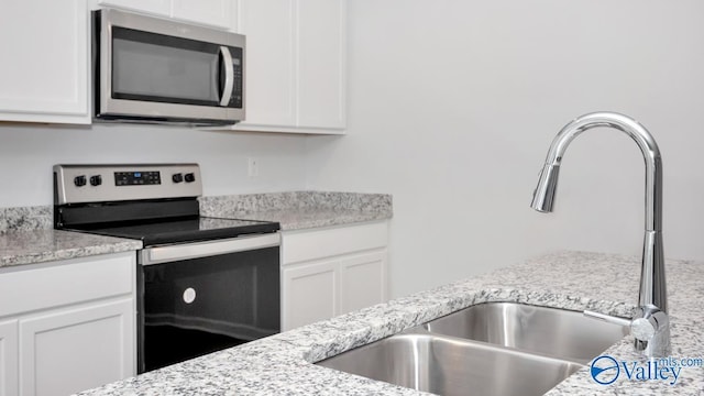 kitchen featuring light stone counters, white cabinetry, sink, and appliances with stainless steel finishes