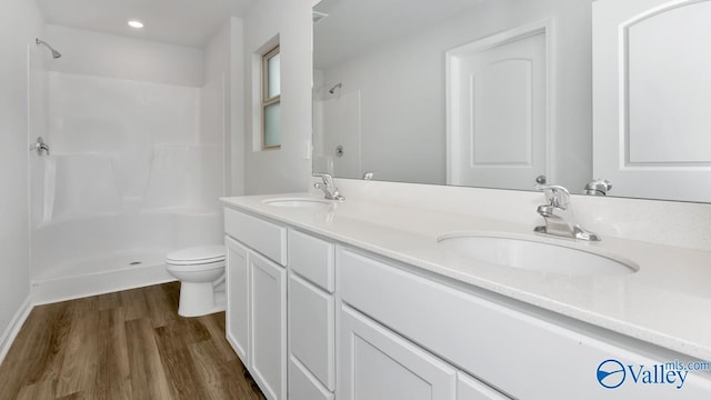 bathroom with wood-type flooring, vanity, toilet, and walk in shower