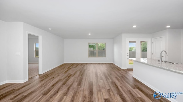 unfurnished living room with hardwood / wood-style flooring and sink