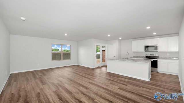 kitchen featuring appliances with stainless steel finishes, sink, wood-type flooring, white cabinetry, and an island with sink