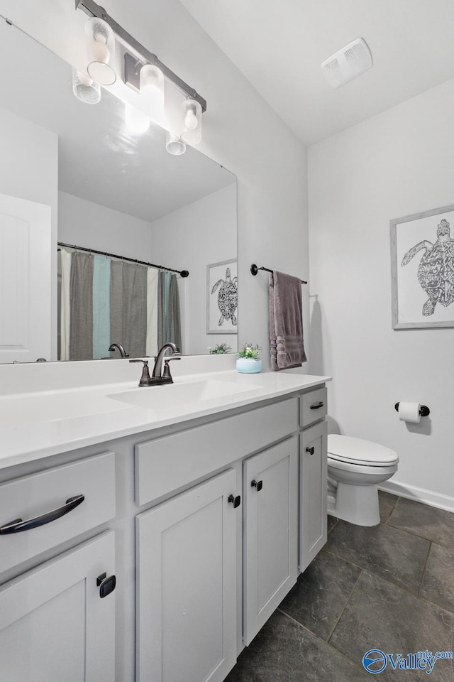 bathroom with toilet, vanity, and visible vents