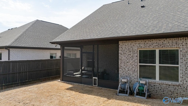 exterior space featuring brick siding, roof with shingles, and a sunroom