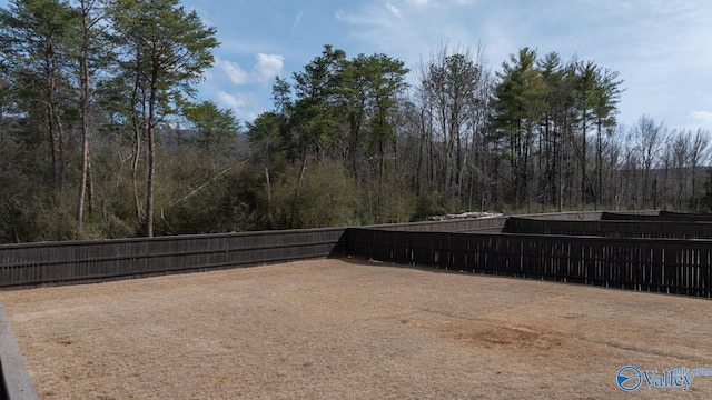 view of yard featuring a forest view and fence