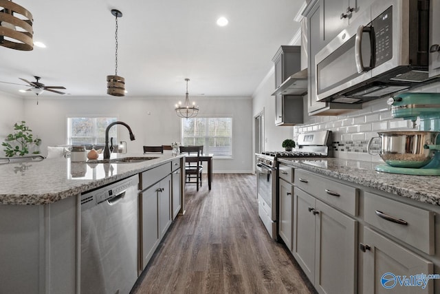 kitchen with dark wood finished floors, a sink, stainless steel appliances, gray cabinetry, and backsplash