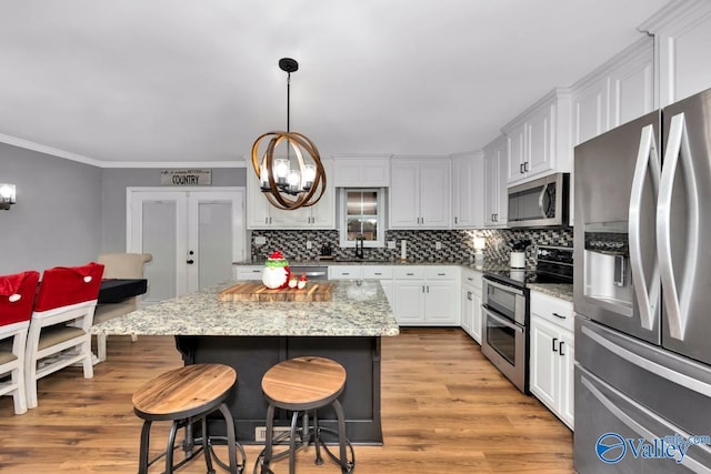 12956 Hickory Hills Rd, Athens, AL 35614 - kitchen featuring light stone countertops, light hardwood / wood-style floors, a kitchen island, white cabinetry, and stainless steel appliances