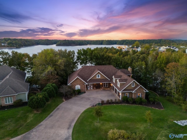 view of front of house with a lawn and a water view