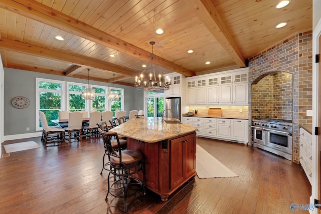 kitchen featuring dark hardwood / wood-style floors, hanging light fixtures, stainless steel appliances, and a center island with sink