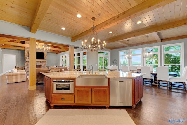 kitchen featuring stainless steel appliances, sink, decorative light fixtures, and a center island with sink