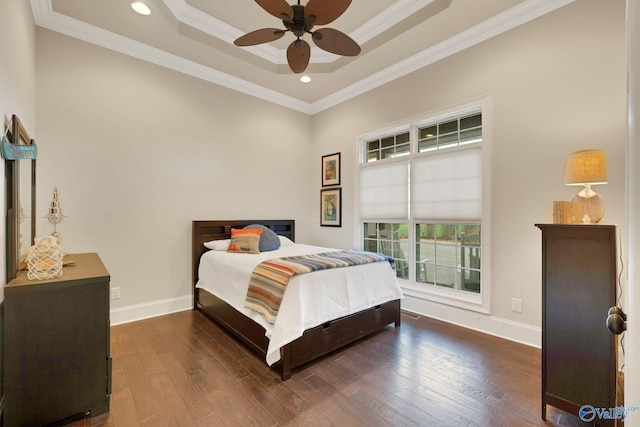 bedroom with ornamental molding, dark wood-type flooring, a tray ceiling, and ceiling fan