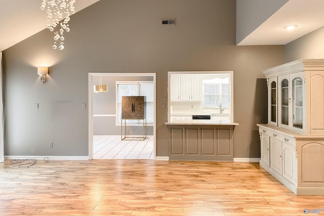 1509 Southampton Ct, Decatur, AL 35601 - kitchen with high vaulted ceiling, light wood-type flooring, baseboards, light countertops, and glass insert cabinets