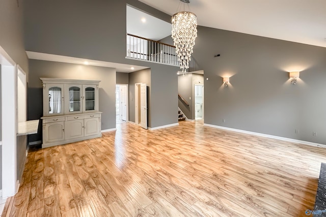 1509 Southampton Ct, Decatur, AL 35601 - unfurnished living room with high vaulted ceiling, a chandelier, stairway, light wood finished floors, and baseboards