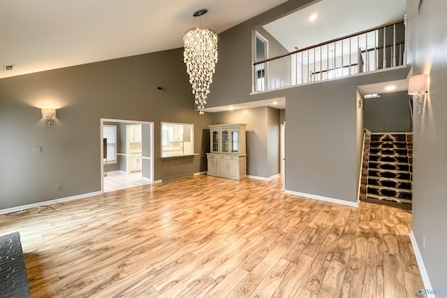 1509 Southampton Ct, Decatur, AL 35601 - unfurnished living room with high vaulted ceiling, a chandelier, light wood-type flooring, and baseboards