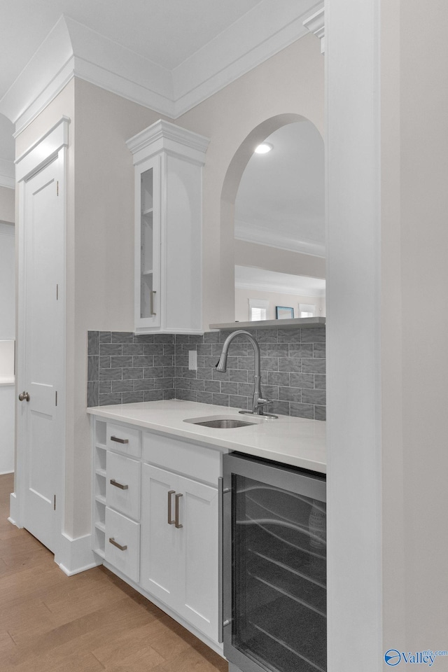 241 Farmhouse Dr, Madison, AL 35757 - bar featuring beverage cooler, a sink, crown molding, light wood finished floors, and decorative backsplash