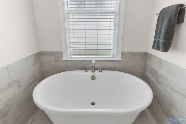 241 Farmhouse Dr, Madison, AL 35757 - bathroom featuring a freestanding tub, tile walls, and wainscoting