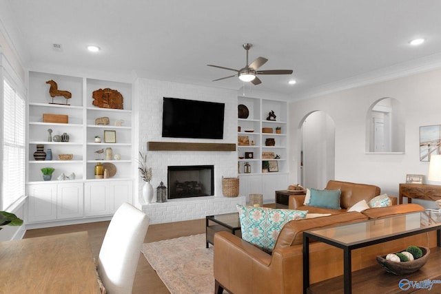 241 Farmhouse Dr, Madison, AL 35757 - living area with arched walkways, ceiling fan, wood finished floors, built in shelves, and ornamental molding