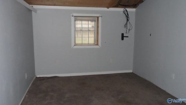 spare room featuring baseboards and dark colored carpet