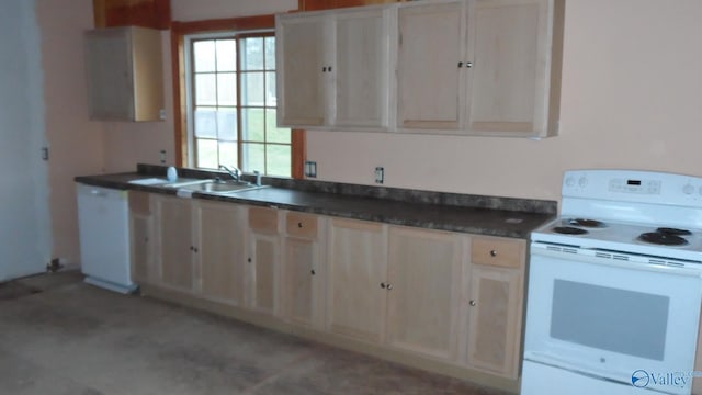 kitchen featuring white appliances, dark countertops, and a sink