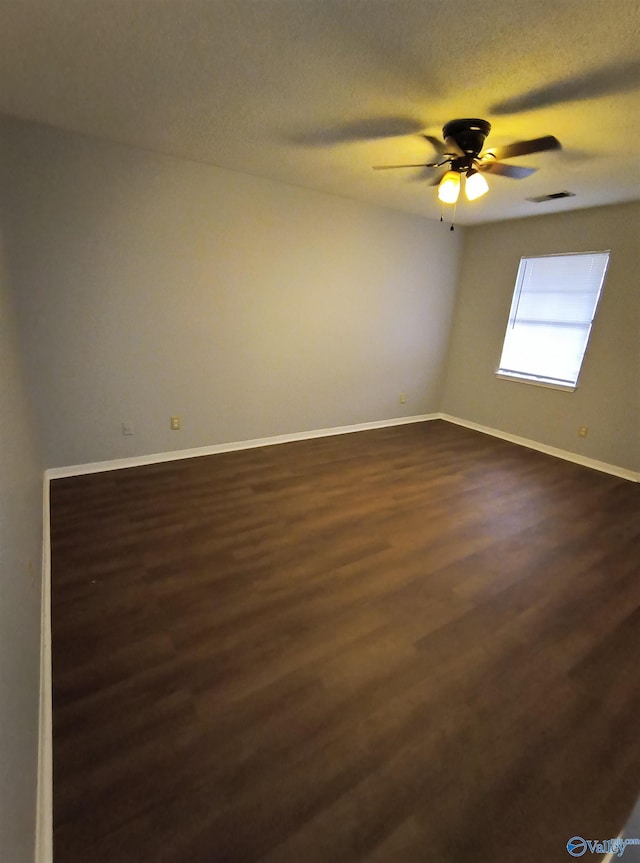 empty room with ceiling fan, dark hardwood / wood-style flooring, and a textured ceiling