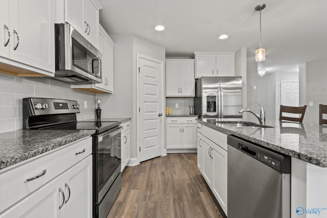 kitchen featuring a sink, decorative backsplash, stainless steel appliances, white cabinetry, and dark wood-style floors