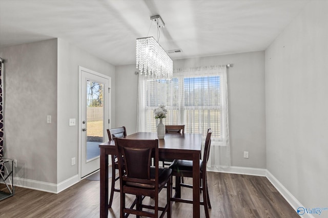 dining area with an inviting chandelier, a healthy amount of sunlight, dark wood-type flooring, and baseboards