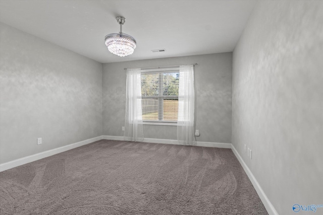 spare room with a chandelier, visible vents, carpet flooring, and baseboards